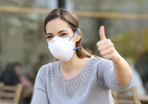 Woman doing thumbs up wearing protective mask