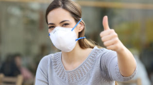 Woman doing thumbs up wearing protective mask